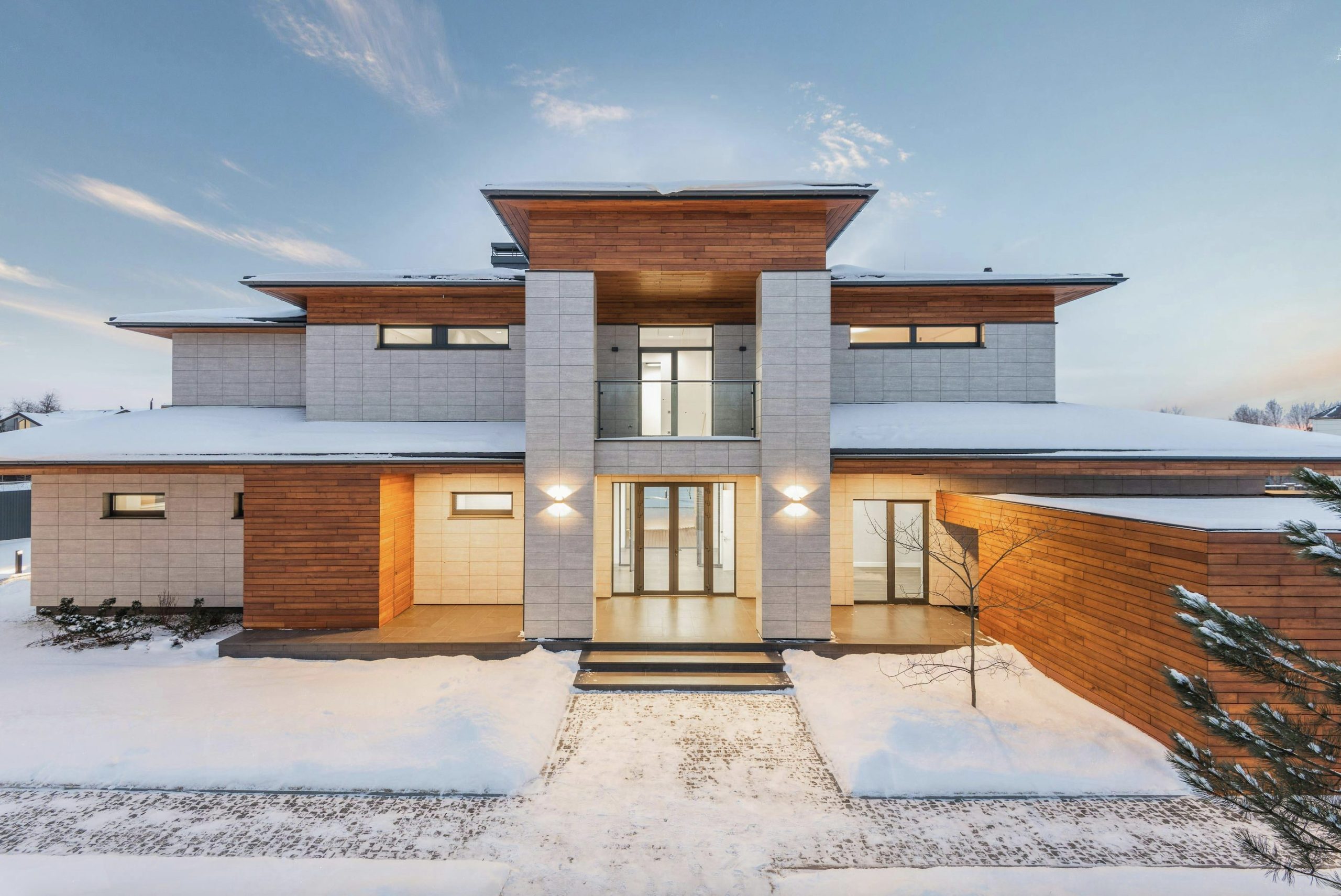Modern luxury home with a sleek architectural design, large glass windows, and wood paneling, set in a snowy landscape, ideal for real estate investment.